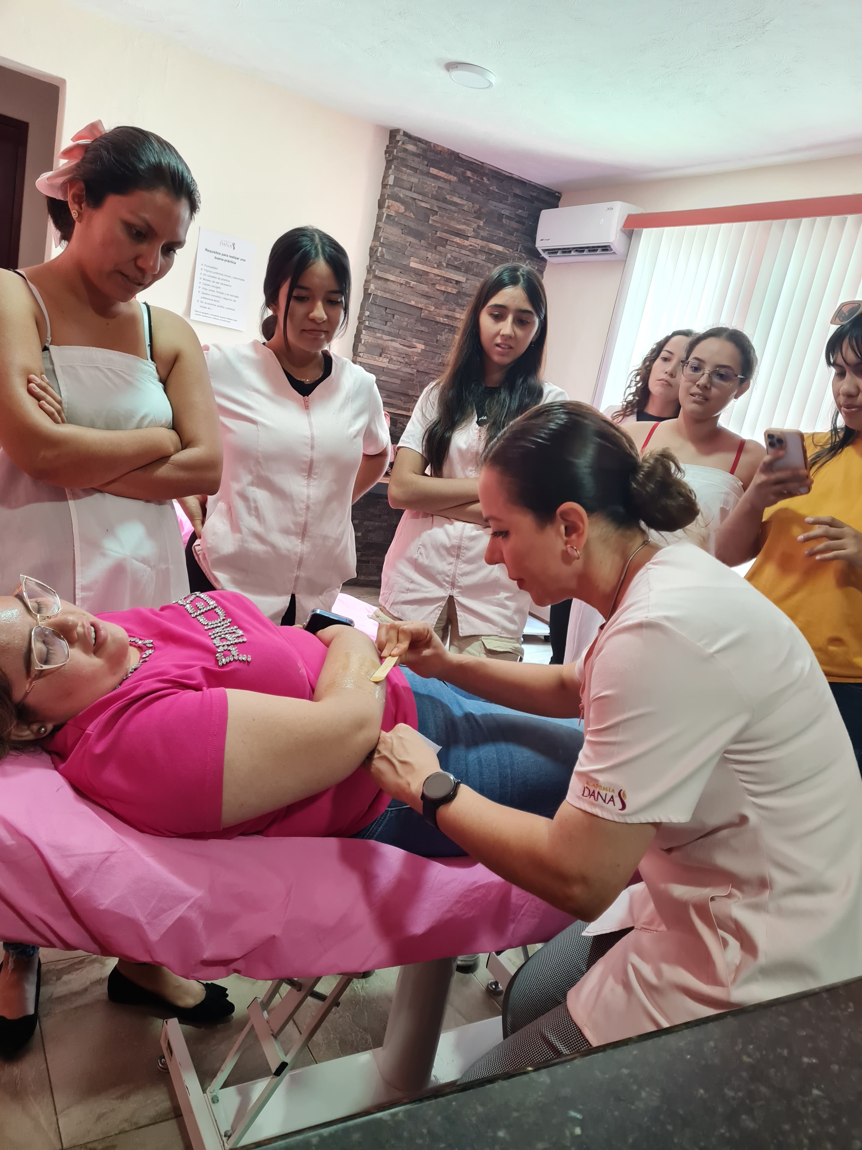 Instructora haciendo una demostración de depilación a alumnas de cosmetologia